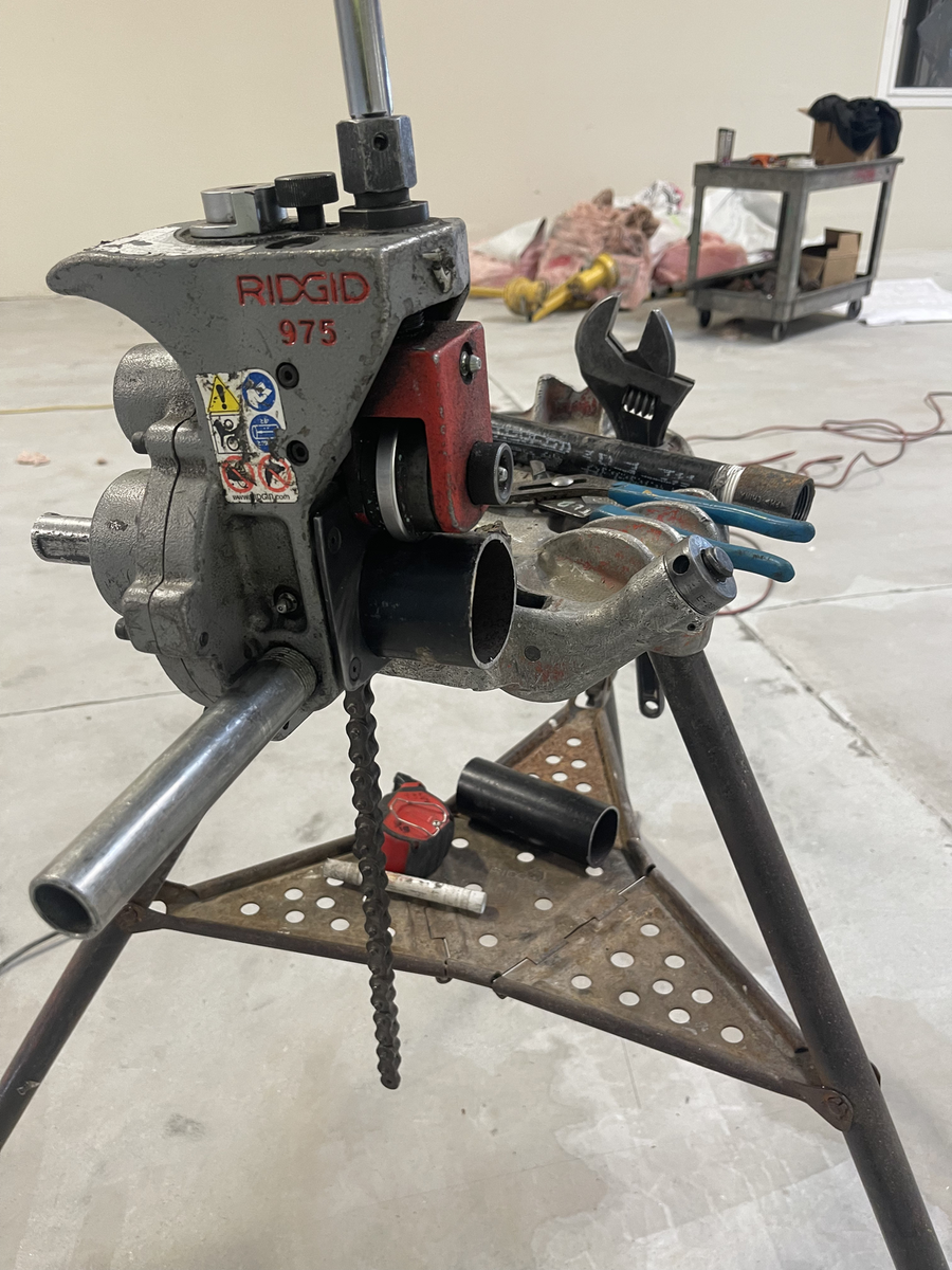 Pipe threading machine set up on a stand at a jobsite